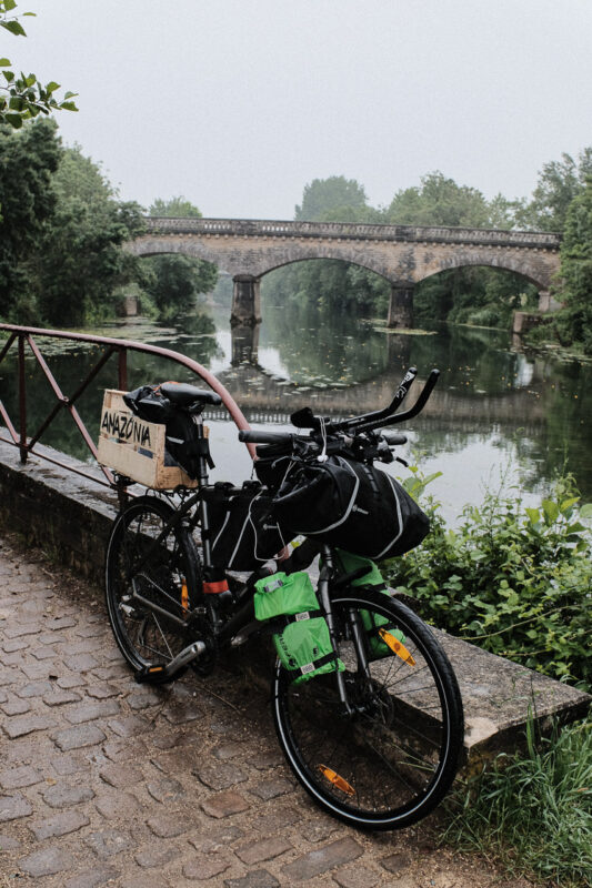 Minha bicicleta nas margens do Sèvre Niortaise com uma ponte antiga
